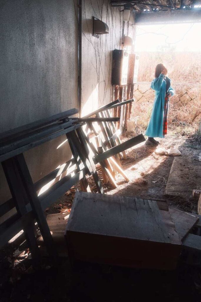 Femme en robe bleue marchant le long d’une passerelle ensoleillée.